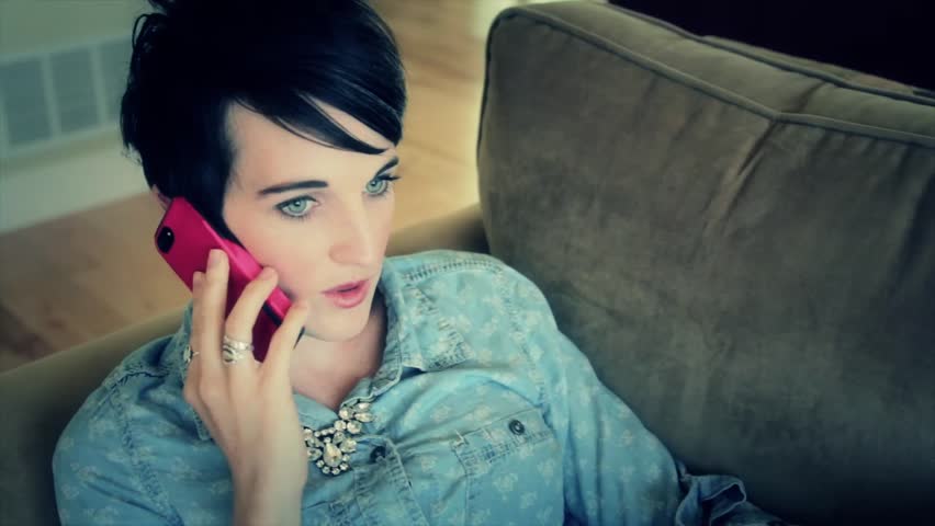 A woman talking on her smart phone while resting on her couch