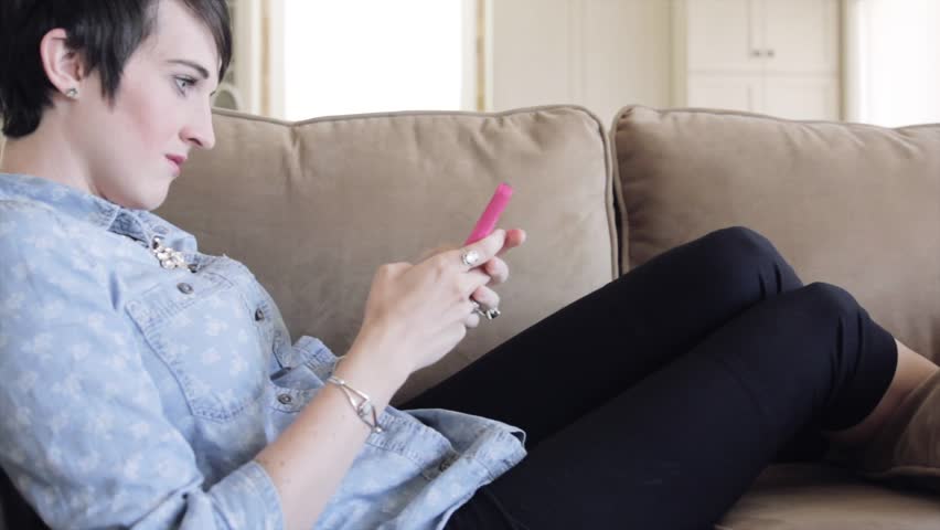 A woman texting while relaxing comfortably on her sofa