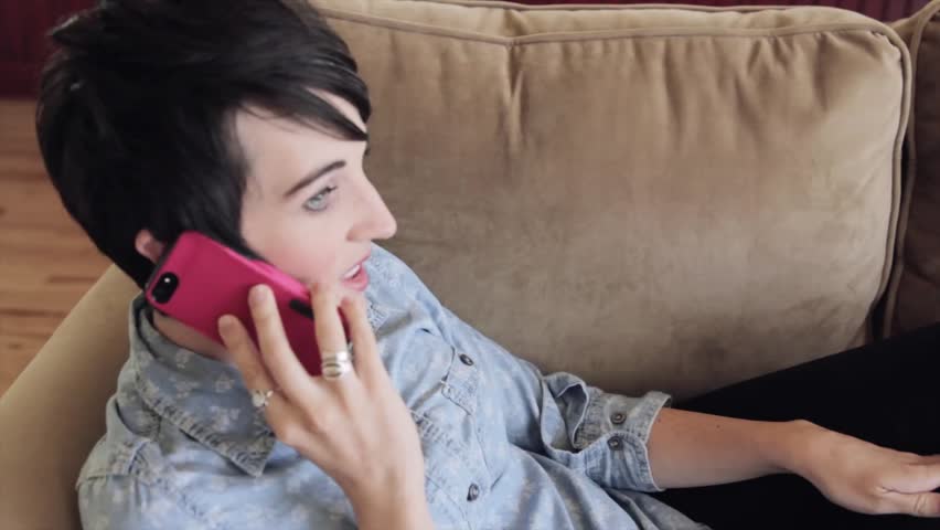 A woman talking on her smart phone while resting on her couch