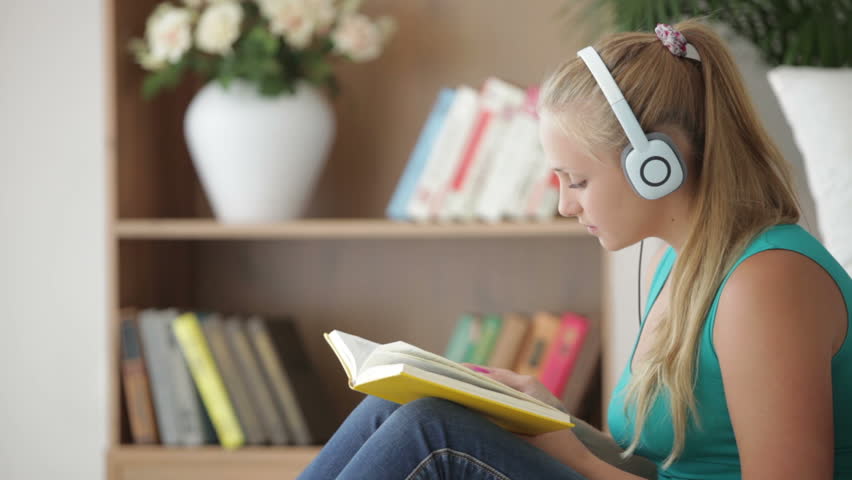 Cute girl listening music and reading book with smile