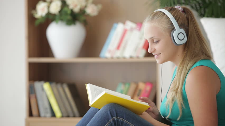 Charming girl reading book and listening music