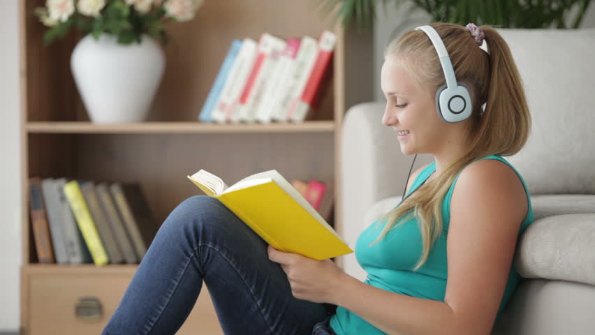 Happy girl reading book and listening music