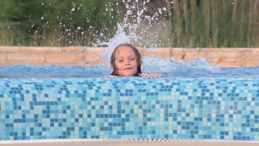 Slow Motion Shot Of A Little Girl Splashing Water In Swimming Pool. She Smiles
