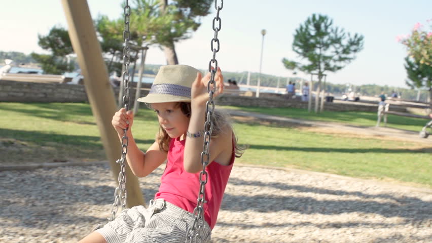 Slow Motion Shot Of A Cute Girl With Fashion Hat Jumping Off A Swing In Park And