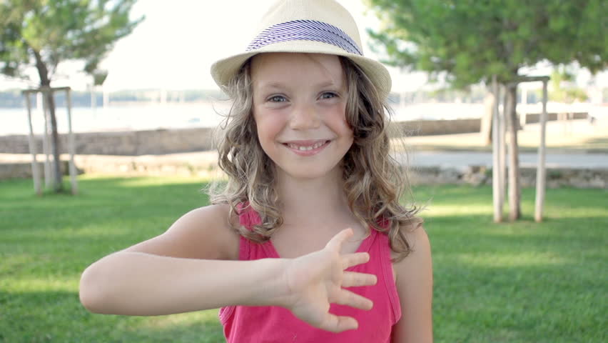 Slow Motion Shot Of A Cute Girl Wearing A Stylish Hat Waving And Smiling At