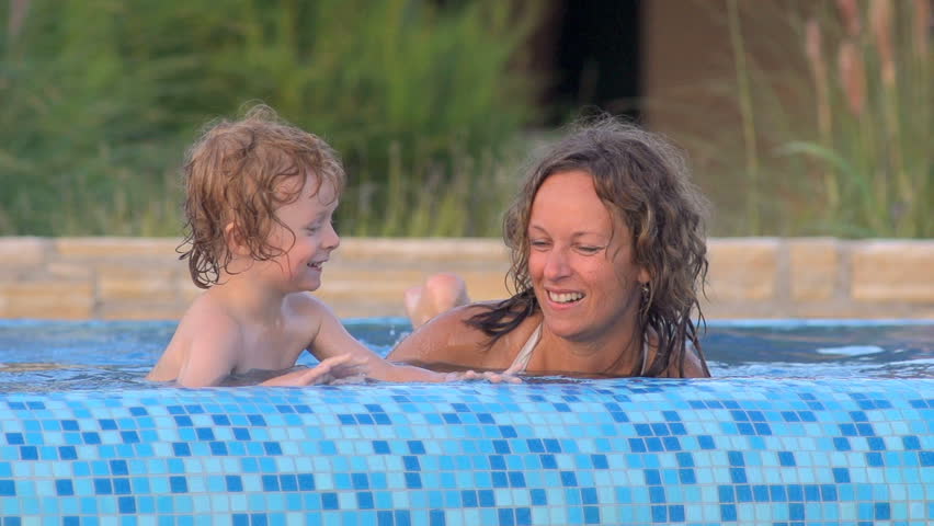 Slow Motion Shot Of A Mother And Three-Year-Old Son Playfully Splashing Water In