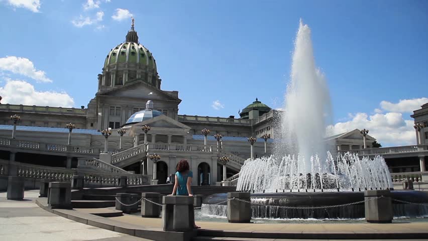 A woman relaxes by a fountain outside the capitol building in Harrisburg,