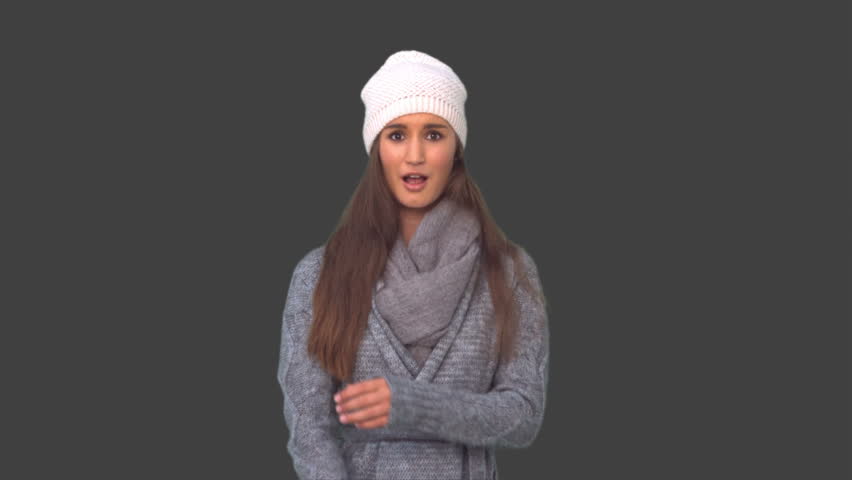 Young model in winter clothes shivering on grey background