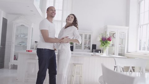 Happy and attractive young mixed race couple viewing a beautiful modern property with a view to making it their home. In slow motion.