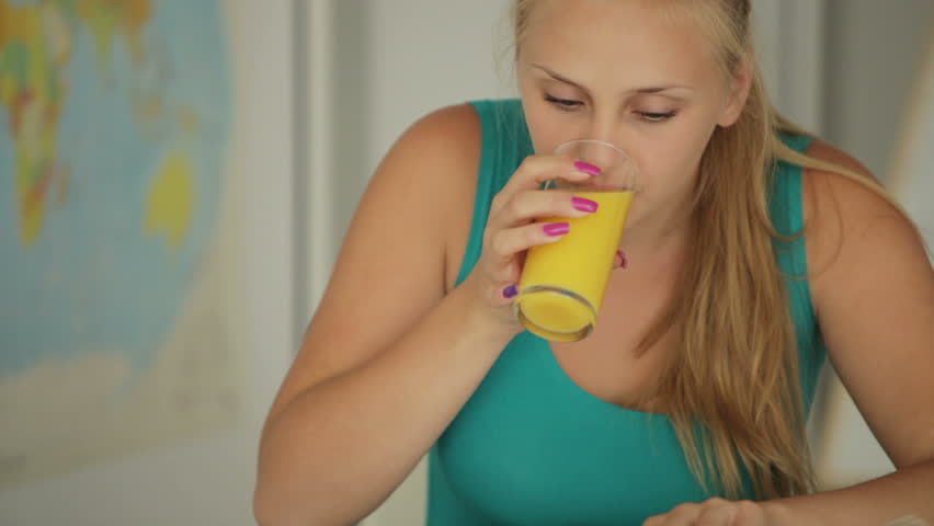 Beautiful girl writing in notebook and drinking juice