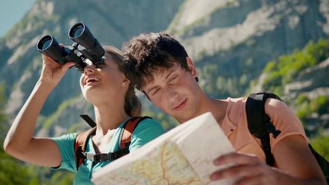 Man and woman during leisure activities on holidays, young people hiking and trekking on mountains, talking, and looking at map with binoculars. Part 3 of 12 Stock Video