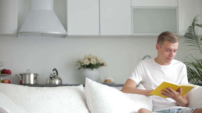 Attractive young men sitting on sofa and reading book