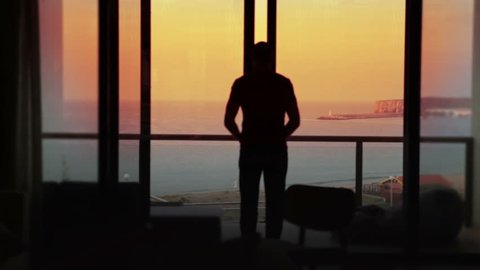 Man opens the doors to his terrace on holiday. Summer vacation at sunset.