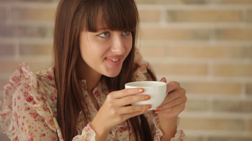 Young woman sitting at cafe smiling and drinking coffee