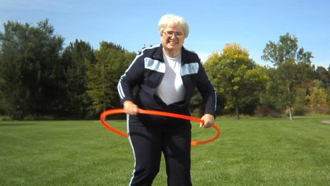 Senior woman at park playing with hula hoop