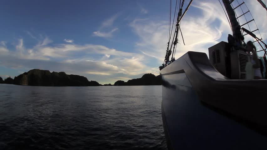An Indonesian pinisi schooner sails toward a set of limestone islands in Raja