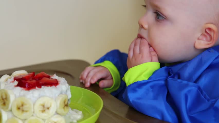 A baby boy eating his first birthday cake at his party