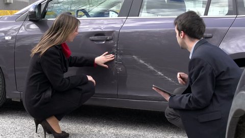 Woman and insurance agent discussing car damage