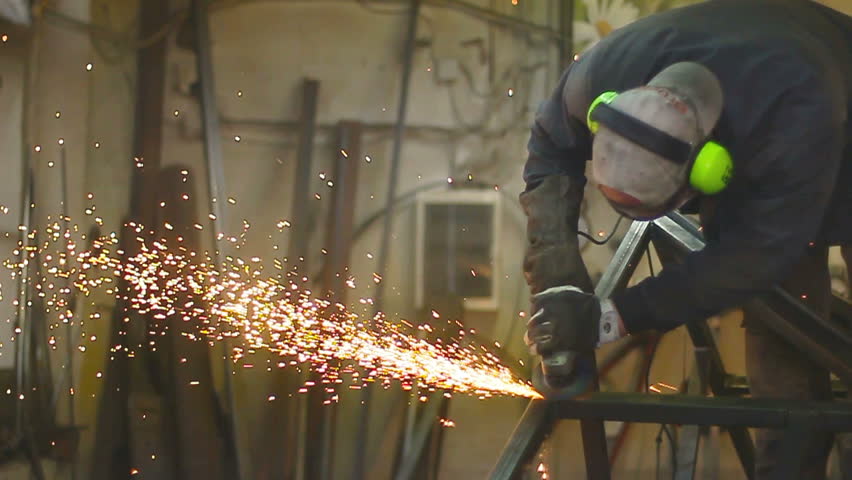 Worker grinding metal construction with a circular saw