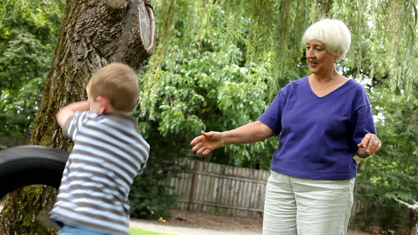 Senior woman spinning young boy on swing