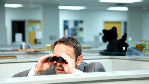 Businessman peeking over cubicle with binoculars