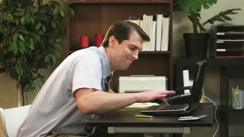 A frustrated businessman starts to smash his computer while in the office. Medium slow motion shot. Royalty-Free Stock Footage #4552010