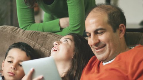 An adorable family sit together and play with a laptop and digital tablet. Close up shot