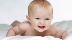 Cute baby boy or girl on its belly smiles for camera in front of a white background.
