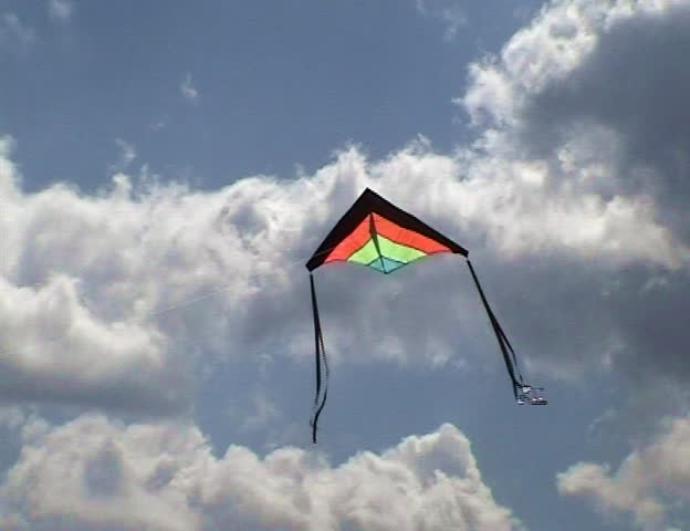 The multi-colored kite flies in the sky