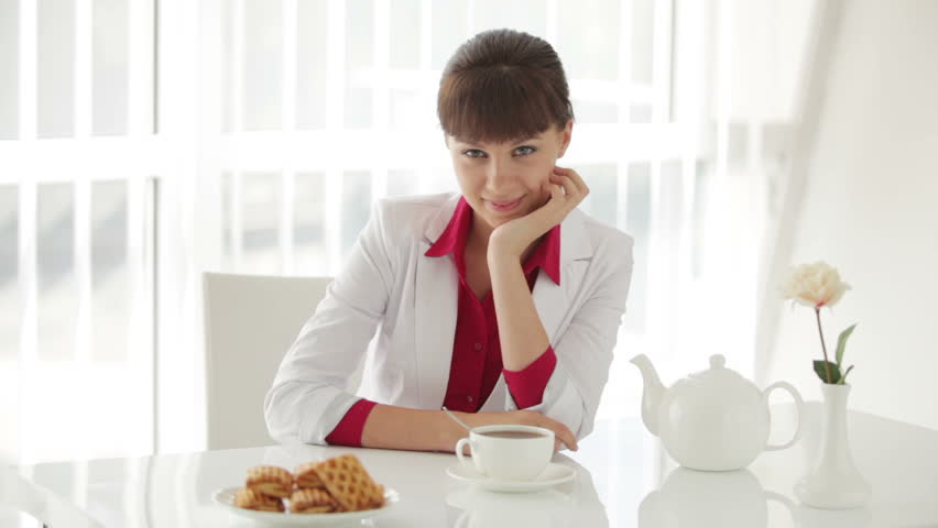 Attractive young woman sitting at table with cup of tea