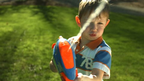 Young boy spraying squirt gun at camera Stock Video