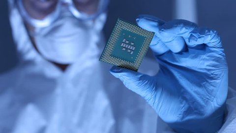 Man in clean room holds up computer cpu microchip