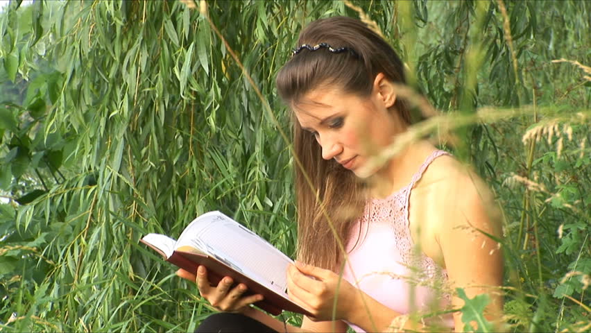 Girl reads the book on the bank of river