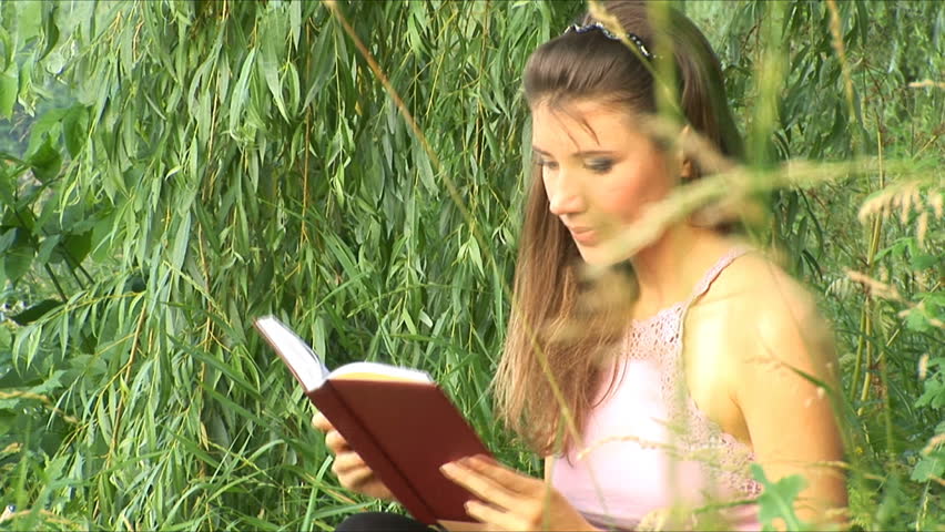 Girl reads the book on the bank of river