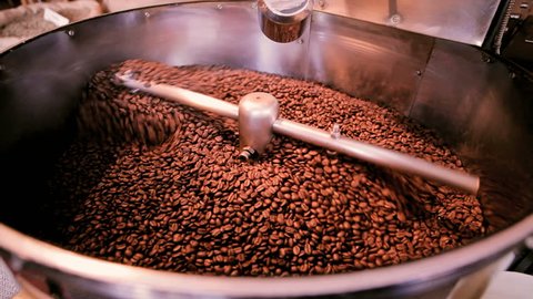 A large machine roasting brown coffee beans in a local cafe.