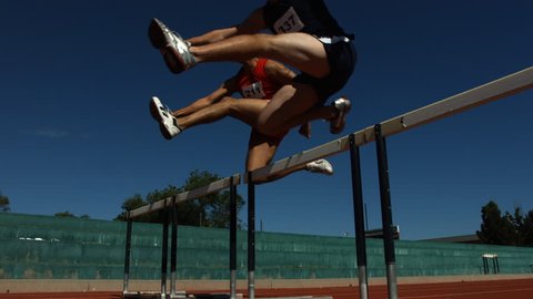Athletes jump over hurdles, slow motion