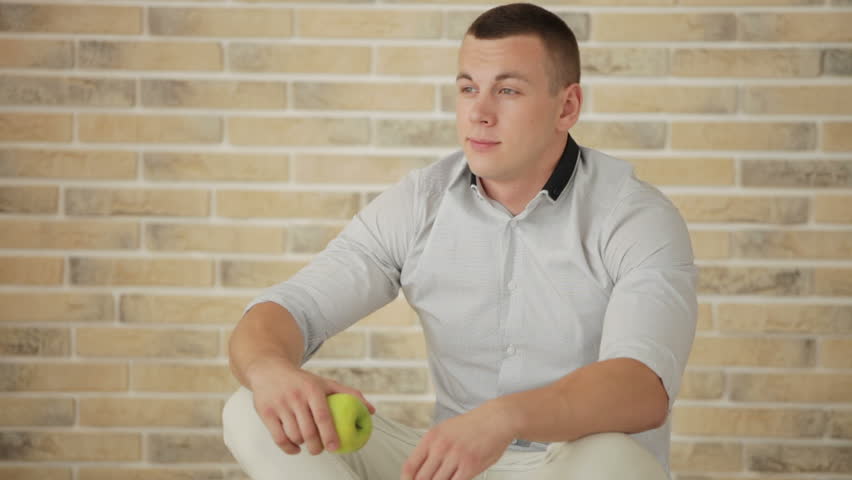 Handsome guy sitting on floor and eating apple