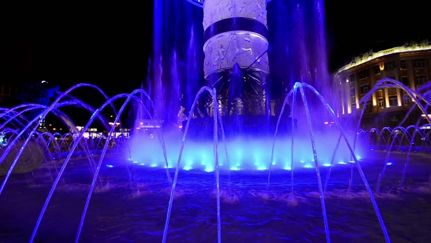 Abstract lit water fountain background of dancing forms. Night shoot of water