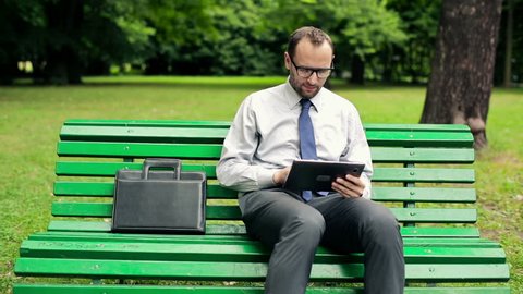 Businessman with tablet computer in the park
