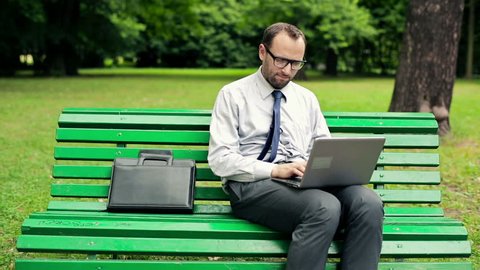 Businessman finishing working on laptop in the park
