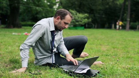 Businessman working on laptop in the park
