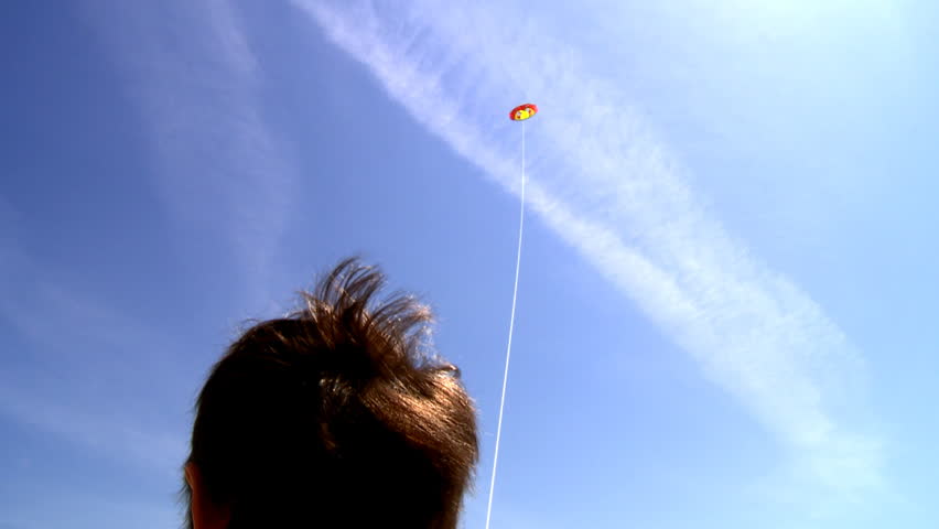 Boy playing with kite over blue sky