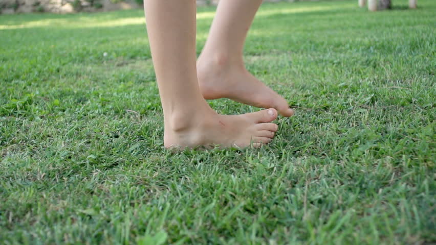 Slow Motion Shot Of A Child's Bare Feet Walking Over Green Grass 