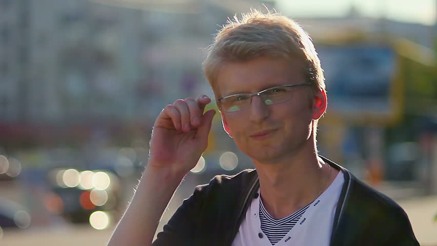 Pleasant young blond man takes off glasses confidently looking