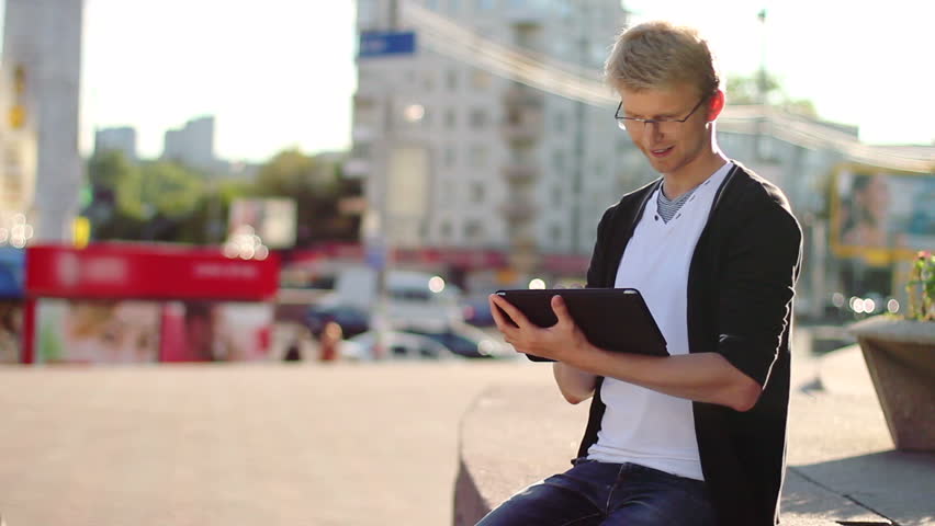 Smiling man reading electronic pad tablet pc, looking at camera