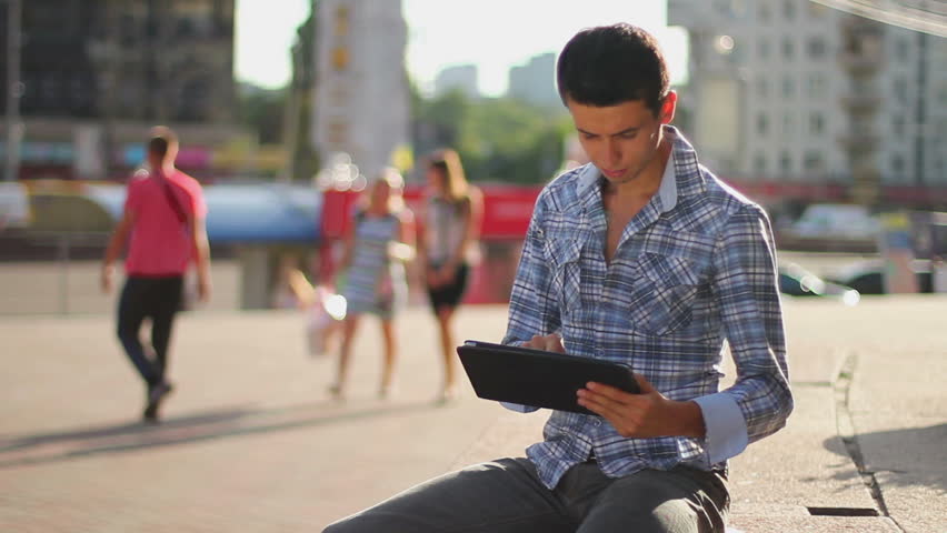 Young business man reading tablet pc computer on city square