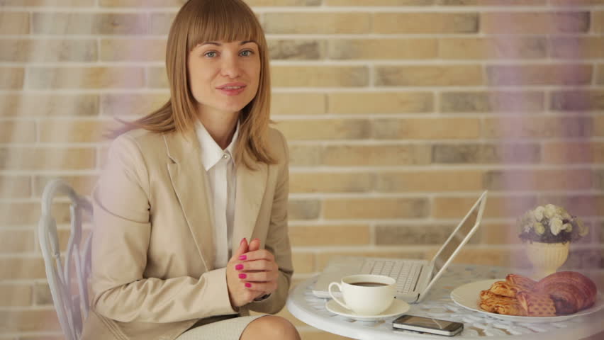 Attractive young woman sitting at cafe with laptop and cup of coffee