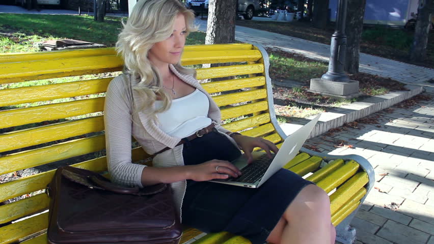 Pretty girl sitting yellow bench typing, social network stedicam