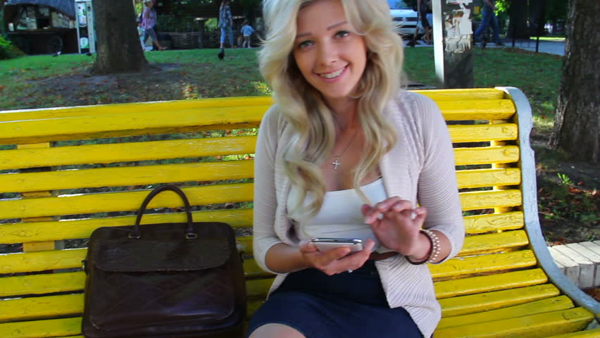 Happy business woman writes message on touch phone in park dolly
