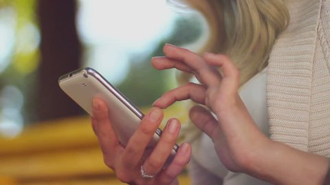 Closeup of young woman hands typing sms scrolling pictures phone